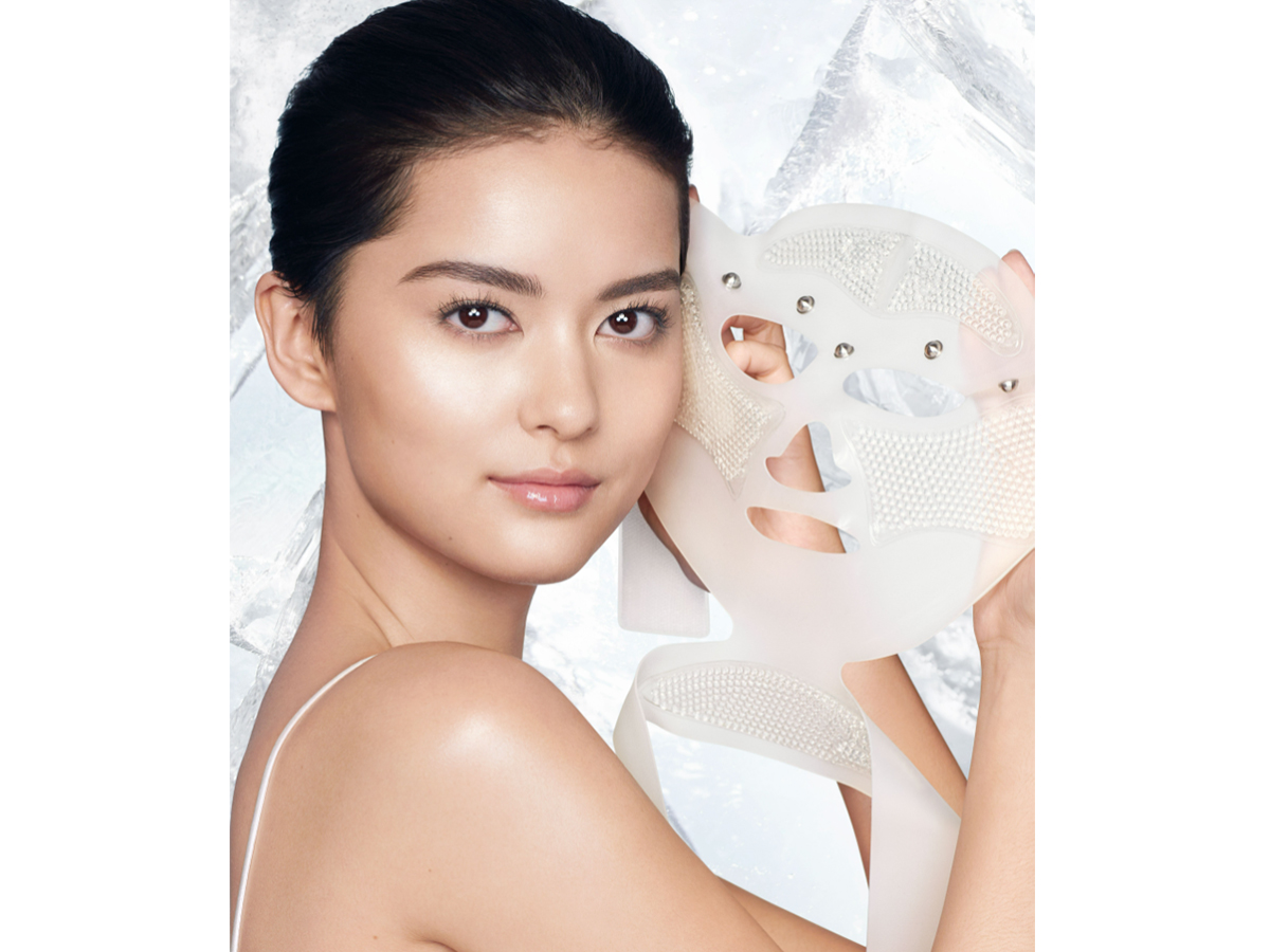 Fair-tone brunette model removing a reusable, white-coloured mask, revealing glowy, flawless, and lifted skin. 
