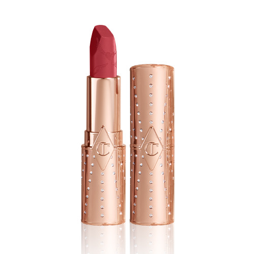 An open, blushed berry-rose lipstick in a metallic, golden-coloured tube with its lid next to it. 