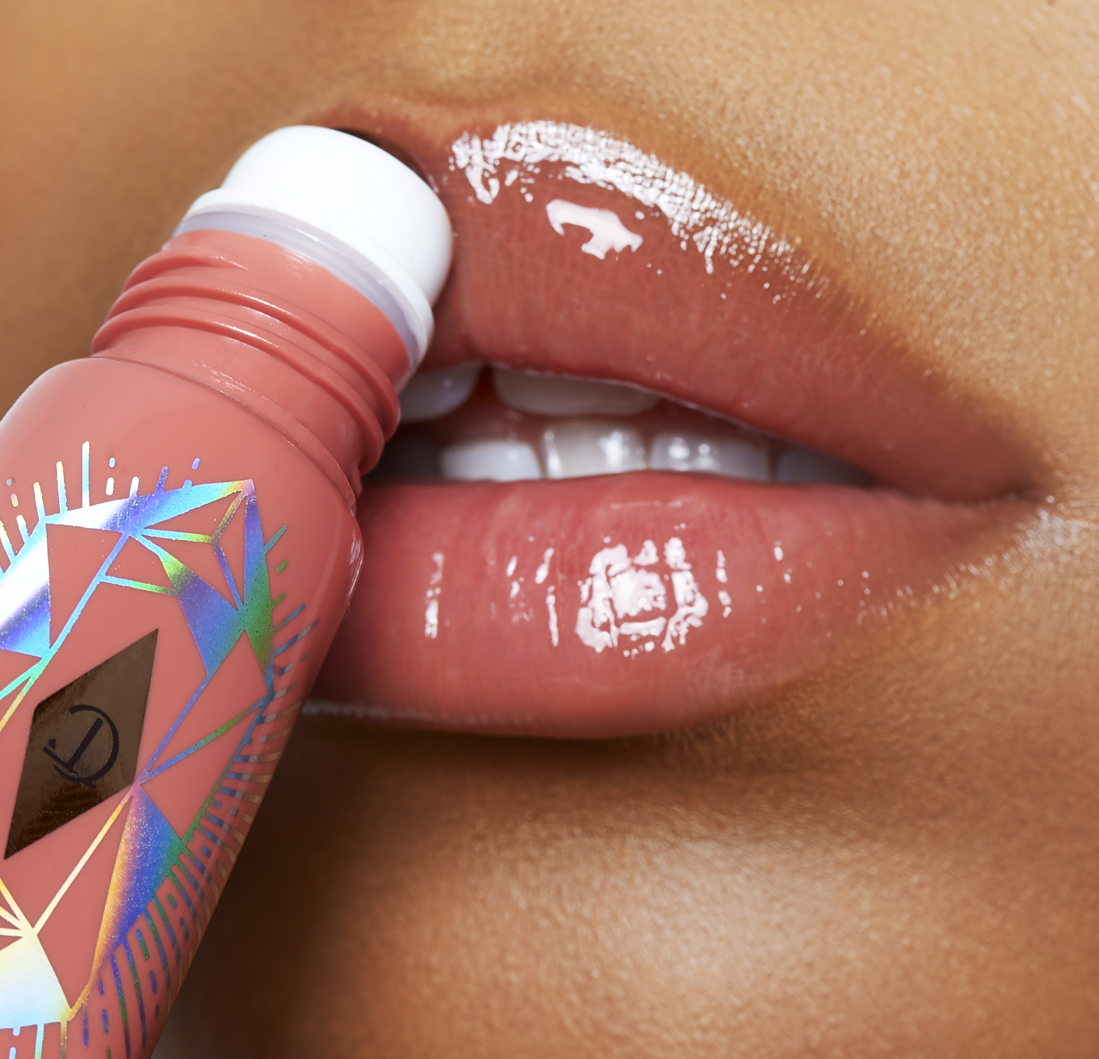 Model applying Charlotte's Magic Lip Oil Crystal Elixir in Rose Lust to hydrate lips