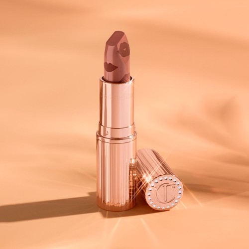  A rosy terracotta coral lipstick with a satin-finish in a gold-coloured tube with its lid next to it.