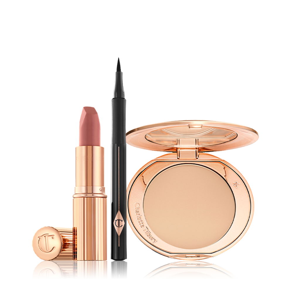 An open nude-pink lipstick in a golden tube with an open black eyeliner pen, and open, mirrored-lid pressed compact in a light shade. 