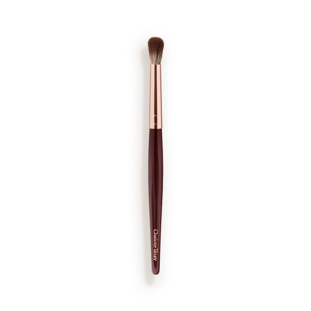 An eyeshadow blending brush with a golden and dark crimson-coloured handle. 