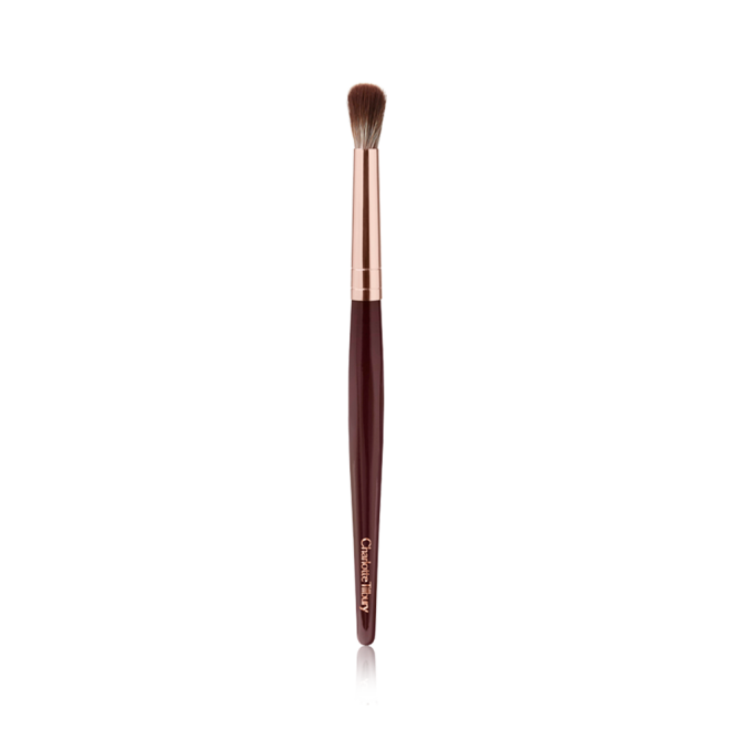 An eyeshadow blending brush with a golden and dark crimson-coloured handle. 