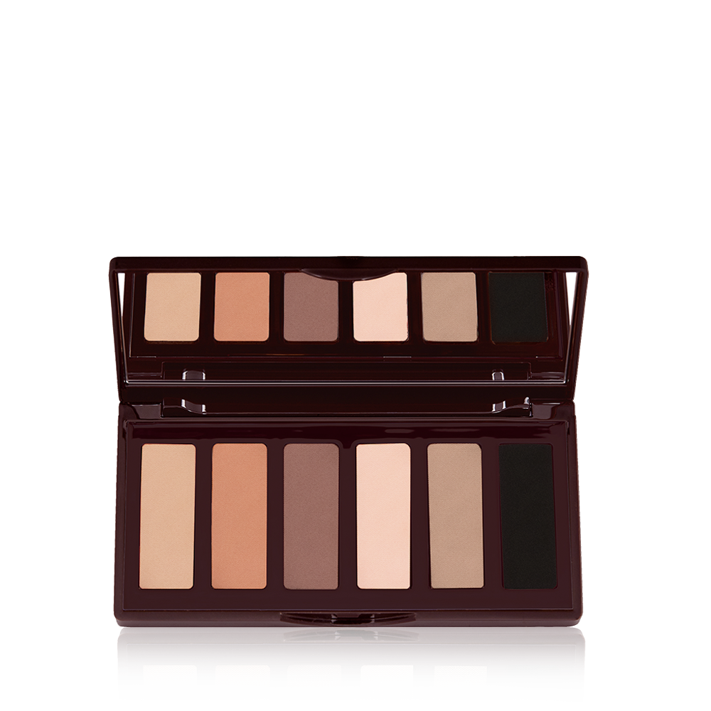 Una paleta de sombras de ojos abierta, con tapa de espejo y 6 compartimentos en tonos nude brillantes y mates. 