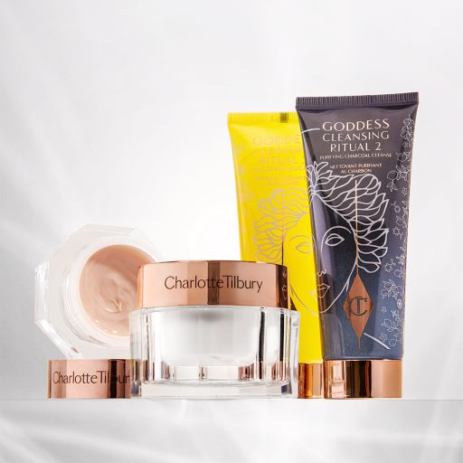 An open eye cream with a face cream, both in glass jars next to two face cleansers, one in yellow packaging and the other black, with all four having metallic, rose-gold coloured lids. 