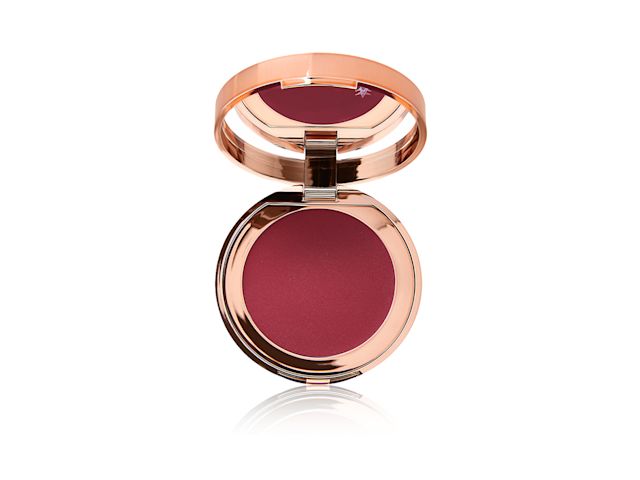 An open, mirrored-lid lip and cheek cream compact in a berry-red shade. 