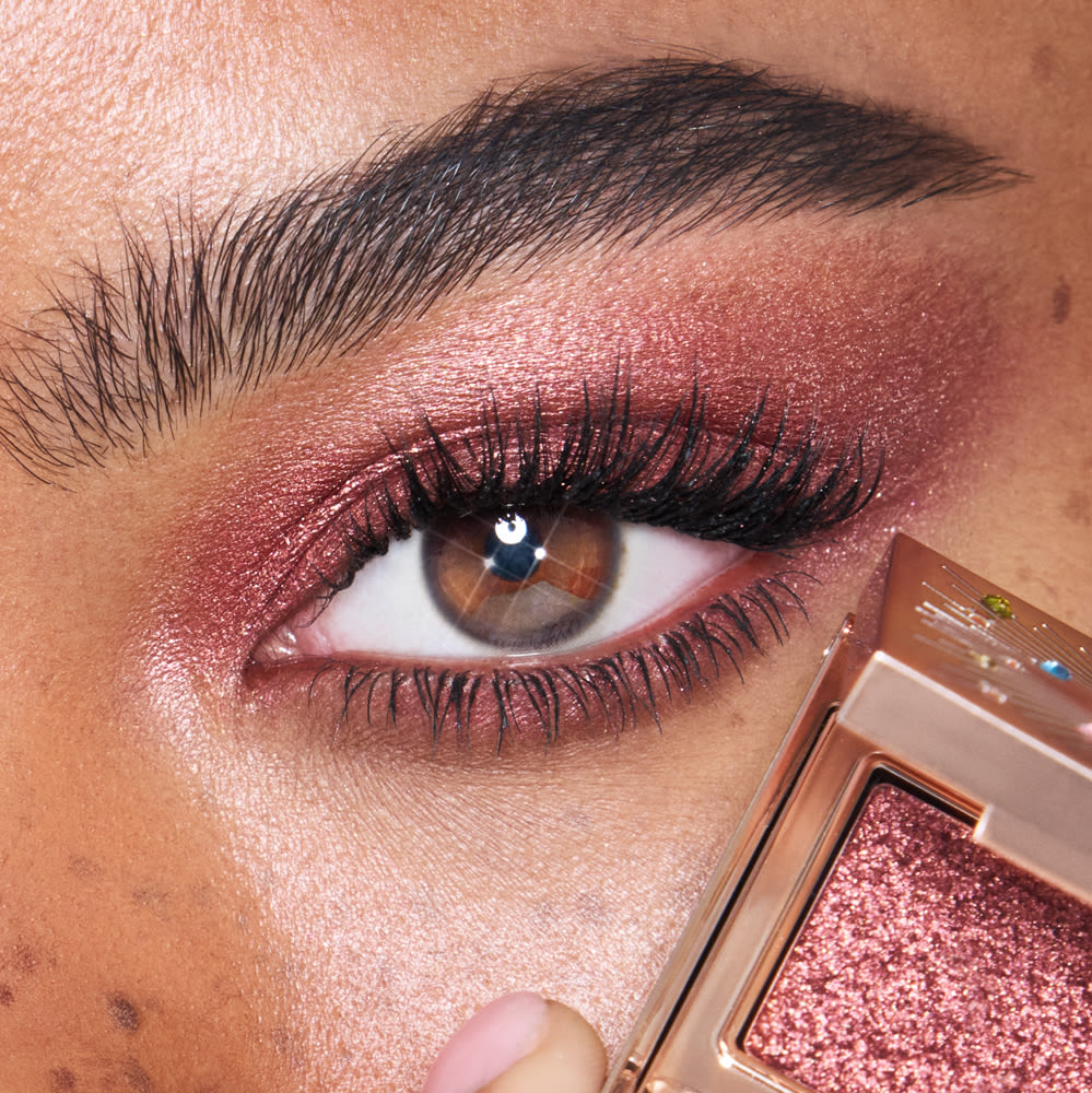 Close-up of a model with brown eyes wearing iridescent rustic red eyeshadow with very fine shimmer. 