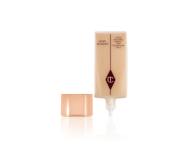 An open, foundation in a light beige colour with its rose gold coloured, metallic lid next to it. 