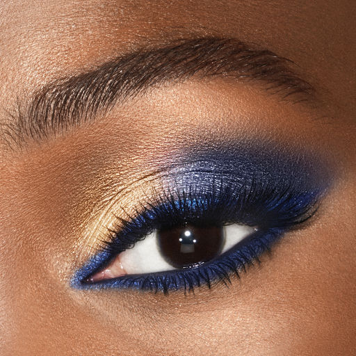 Deep tone close-up of a shimmery, royal blue and golden eye look on dark brown eyes. 