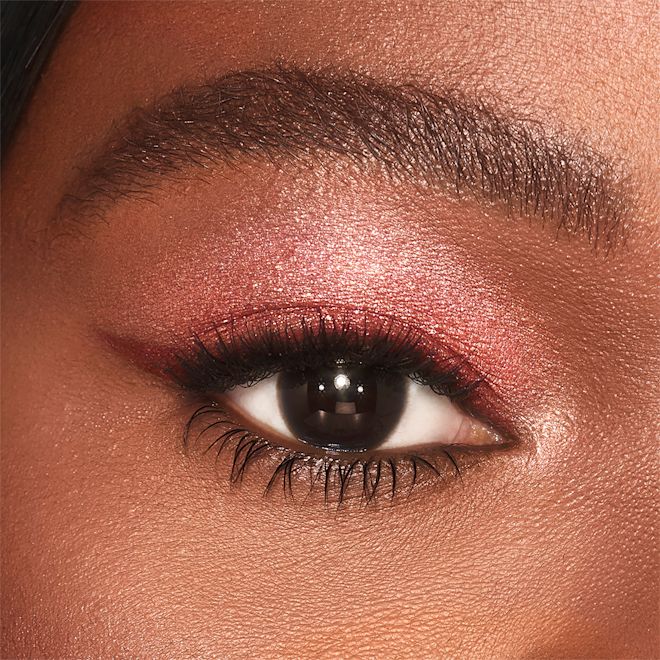 Jewel Pot in Walk of No Shame on deep tone model close-up Single-eye close-up of a deep-tone model with brown eyes wearing shimmery berry-pink eyeshadow.