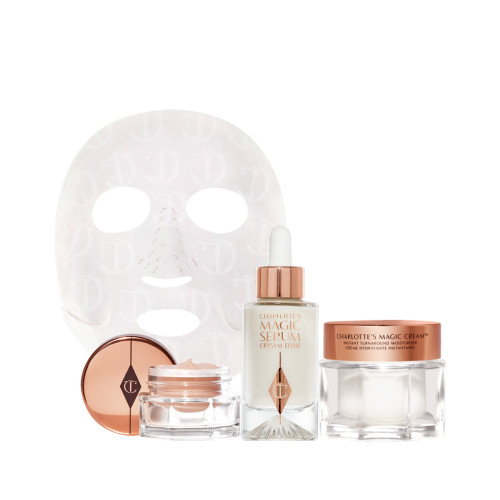 Eye cream in an open glass pot with a gold-coloured lid, dry sheet mask, luminous, ivory-coloured serum in a glass bottle with a white and gold-coloured dropper lid, pearly-white face cream in a glass jar with a gold-coloured lid. 