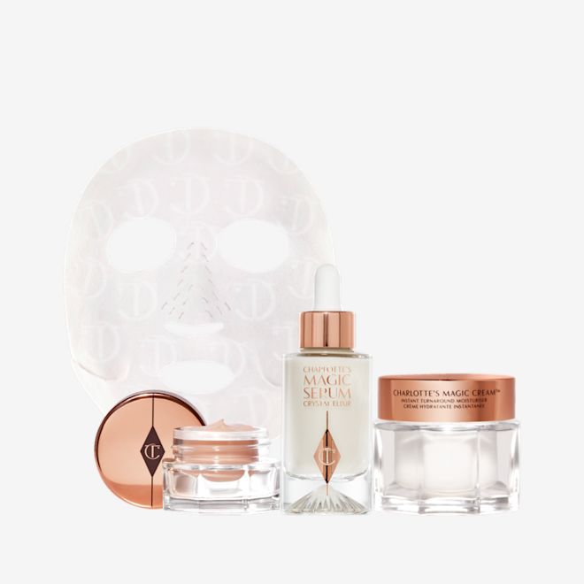 Glowing Night in a Box displayed Eye cream in an open glass pot with a gold-coloured lid, dry sheet mask, luminous, ivory-coloured serum in a glass bottle with a white and gold-coloured dropper lid, pearly-white face cream in a glass jar with a gold-coloured lid.