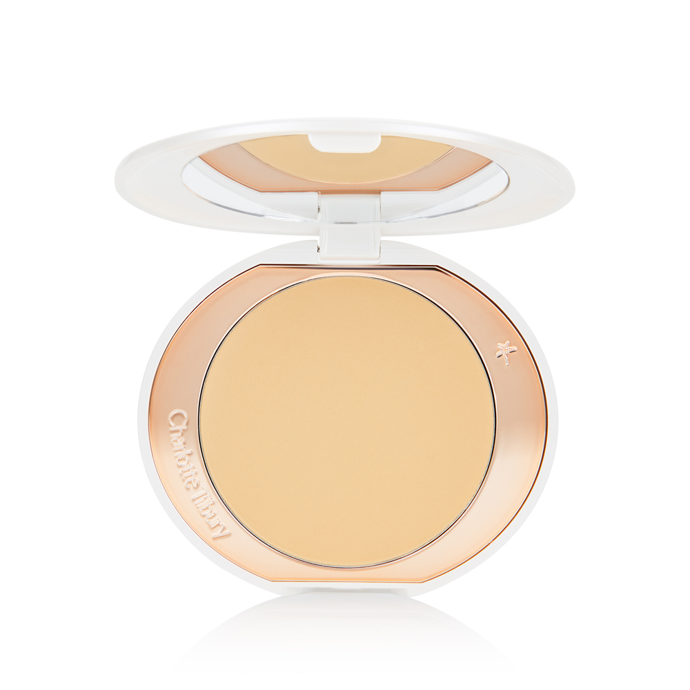 An open, setting powder compact in banana-yellow with a mirrored-lid and white and gold-coloured packaging.