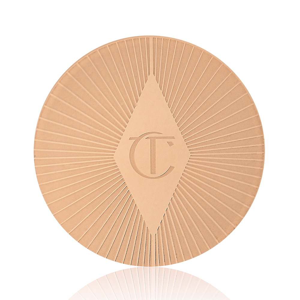 Close-up of a gold-coloured lip scrub lid with a starburst pattern on top and the CT logo printed in the middle.