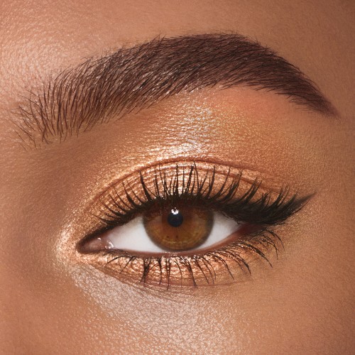 Single-eye close-up of a deep-tone model with brown eyes wearing warm sunset gold cream eyeshadow.