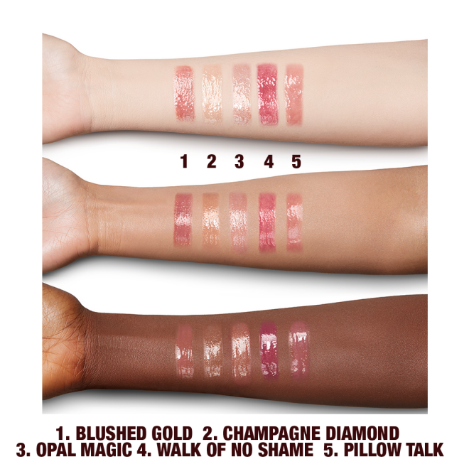 Fair, tan, and deep-tone arms with swatches of five shimmery lip glosses in shades of pink, champagne, peach, and gold. 