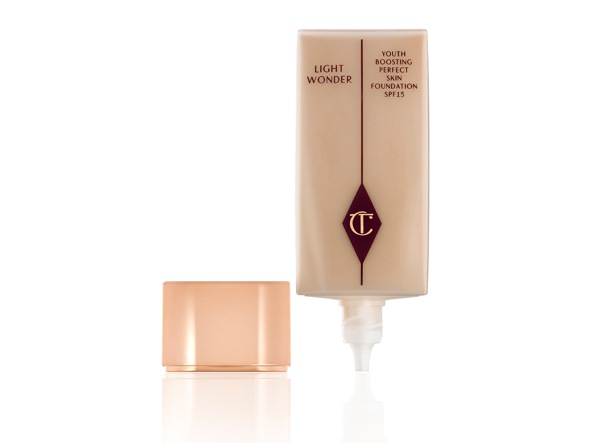 An open, foundation bottle in a light beige colour with the CT logo printed on it and its rose-gold-coloured lid next to it. 