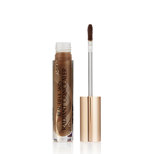 Dark brown radiant concealer in a glass tube with its gold-coloured lid with a doe-foot end next to it, and text on the tube that reads, 'Beautiful Skin Concealer'