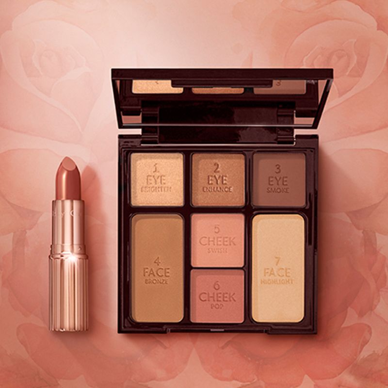 An open matte revolution lipstick in golden peach colour with an open, mirrored-lid face palette with nude eyeshadows, blushes, highlighter, and bronzer. 