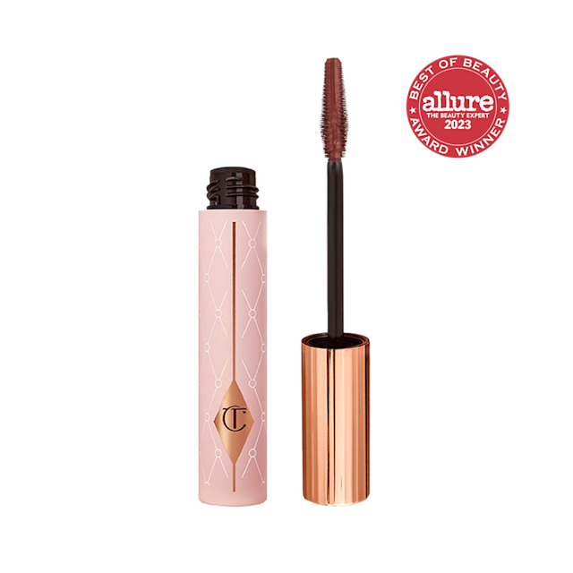 An open tube of a chocolate-brown-coloured mascara in a pink-coloured tube with a gold-coloured lid. 