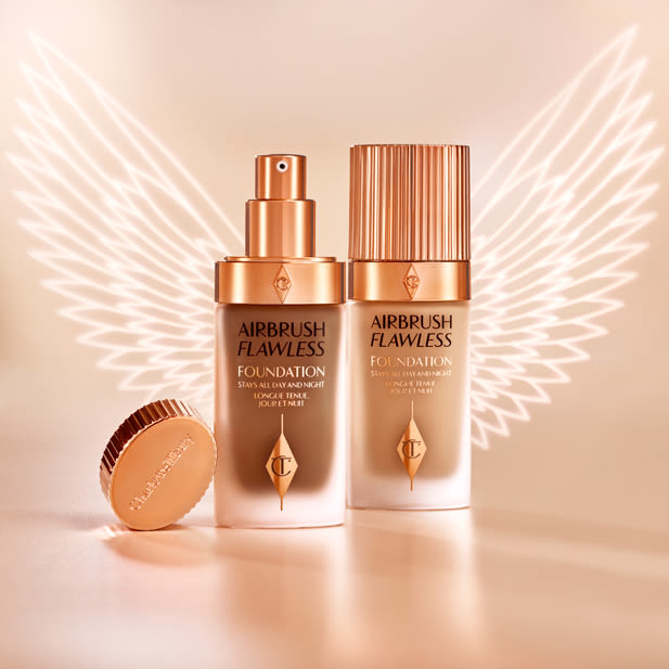 Dark and light foundations, one with its lid and the other with lid removed, in frosted glass bottles with gold-coloured pump dispensers and gold-coloured lids. 