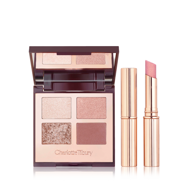 An open, mirrored-lid quad eyeshadow palette in shimmery and matte nude shades with an open, glitter lipstick in nude pink and a closed lipstick, both in golden-coloured tubes. 