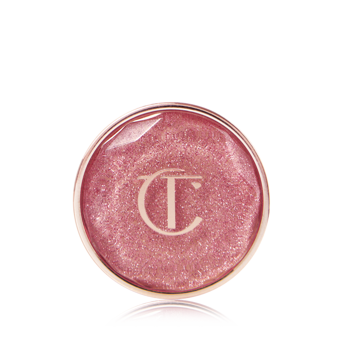 A nude pink shimmery eyeshadow pigment in a glass pot with a translucent lid. 