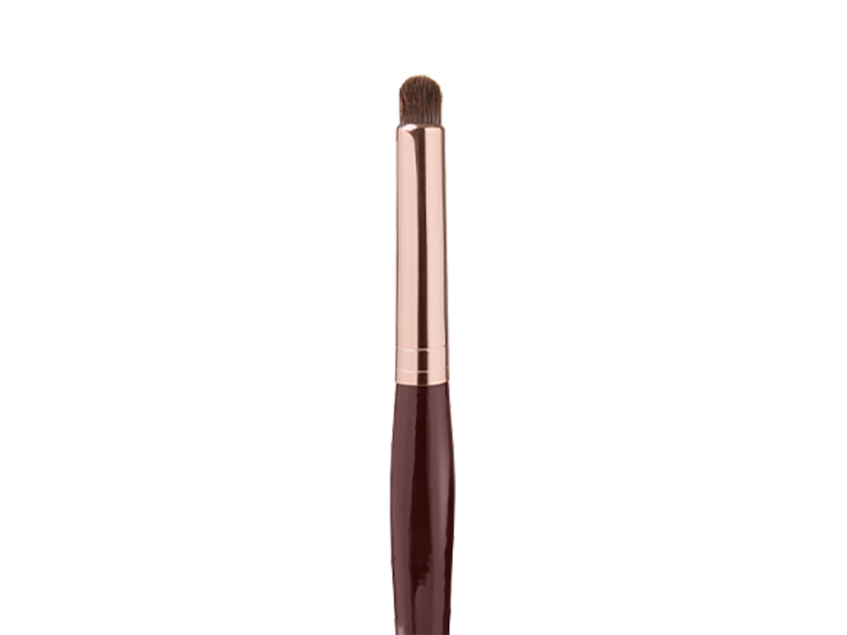 Close-up of an eyeshadow smudging brush in a dark crimson and gold colour scheme. 
