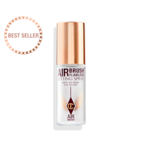 A closed, travel-size setting spray in a clear bottle with a gold-coloured lid.