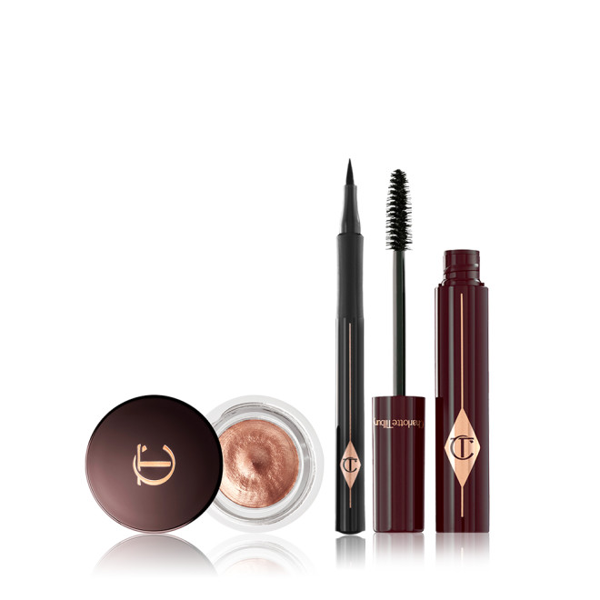 An open, copper-coloured cream eyeshadow in a glass pot with an open, black eyeliner pen, and an open mascara in dark crimson packaging with the applicator next to it. 