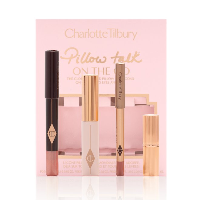 Pillow Talk On The Go with box displayed An unpacked makeup kit that includes an eyeshadow pencil in a rose gold shade, mascara, lip liner pencil in nude pink, and lipstick in a nude pink shade with the packaging box in a nude pink colour behind the products.