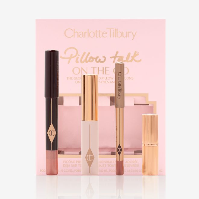Pillow Talk On The Go with box displayed An unpacked makeup kit that includes an eyeshadow pencil in a rose gold shade, mascara, lip liner pencil in nude pink, and lipstick in a nude pink shade with the packaging box in a nude pink colour behind the products.
