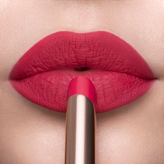 Limitless Lucky Lips in Raspberry Charm on fair-tone lips close-up Lips close-up of a fair-tone model applying a soft pink-red lipstick with a matte finish.