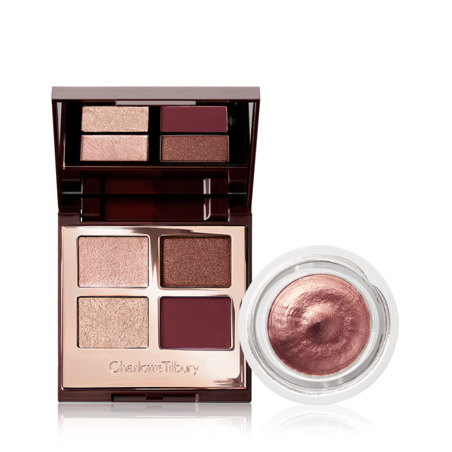 An open, mirrored-lid eyeshadow palette with four shimmery and matte eyeshadows in champagne, rose gold, dark brown, and smokey red shade with an open pot of cream eyeshadow in a dark rose gold shade. 