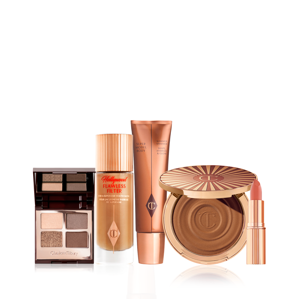 AN open, quad eyeshadow palette wit a mirrored lid, glowy primer in a frosted glass bottle, body highlighter wand, cream bronzer compact, and nude pink lipstick in a gold-coloured tube.