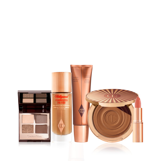 AN open, quad eyeshadow palette wit a mirrored lid, glowy primer in a frosted glass bottle, body highlighter wand, cream bronzer compact, and nude pink lipstick in a gold-coloured tube.