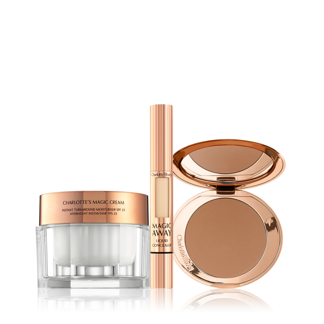 An open, mirrored-lid bronzer compact in a medium-brown shade, a liquid concealer in a golden-coloured tube with a small window on the tube to view the shade inside, and pearly-white face cream in a glass jar with a golden-coloured lid. 