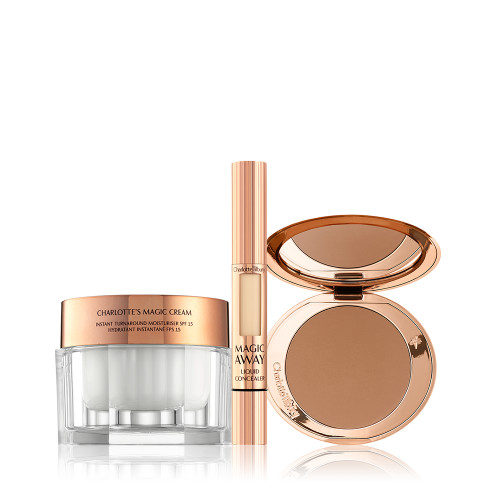 An open, mirrored-lid bronzer compact in a medium-brown shade, a liquid concealer in a golden-coloured tube with a small window on the tube to view the shade inside, and pearly-white face cream in a glass jar with a golden-coloured lid. 