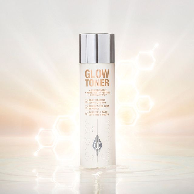 A large, clear bottle filled with luminous, cream-coloured watery toner with a silver-coloured lid.