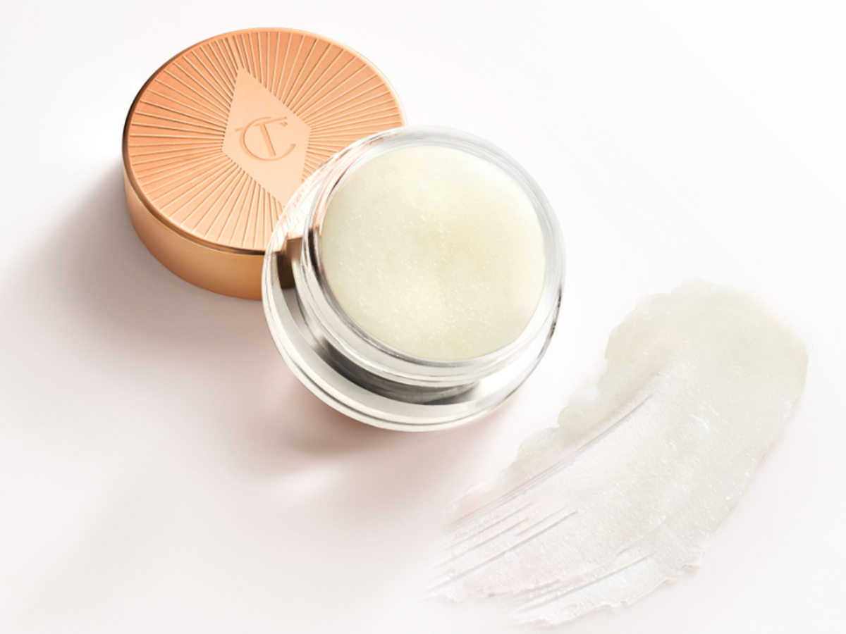 An open pot filled with a thick, white-coloured lip scrub with its gold-coloured lid next to it.