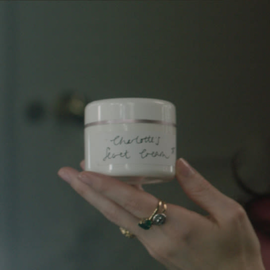 A woman holding the original backstage magic cream, housed in a white jar. 