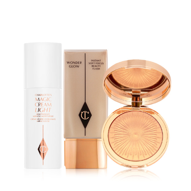 Pearly-white face cream in a glass jar with a gold-coloured lid, foundation in a clear bottle with a gold-coloured lid, and powder highlighter in a soft rose-gold shade in a gold-coloured compact with a mirrored-lid.
