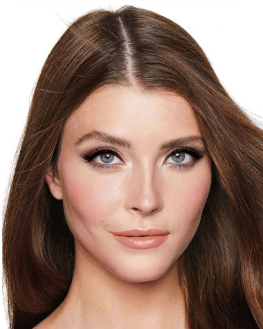 A fair-tone model with blue eyes wearing smokey brown eye makeup with muted pink blush with glossy soft-brown lips.