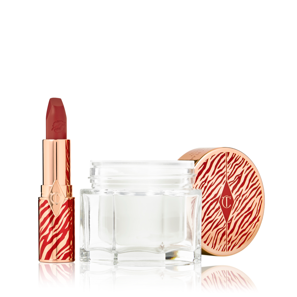 An open lipstick tube in a vivid red shade in a gold-coloured tube with red tiger stripes on it and an open glass jar of pearly-white cream with its gold-coloured lid with red tiger stripes on it for the Lunar New Year. 