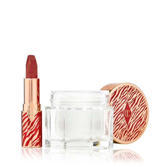 An open lipstick tube in a vivid red shade in a gold-coloured tube with red tiger stripes on it and an open glass jar of pearly-white cream with its gold-coloured lid with red tiger stripes on it for the Lunar New Year. 