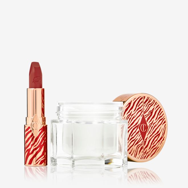 Lucky New Year Magic Duo open An open lipstick tube in a vivid red shade in a gold-coloured tube with red tiger stripes on it and an open glass jar of pearly-white cream with its gold-coloured lid with red tiger stripes on it for the Lunar New Year.