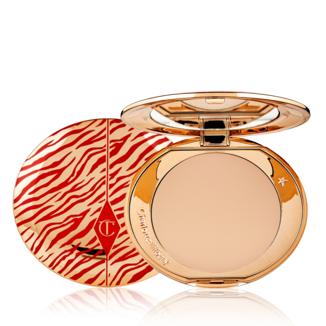 An open, pressed powder compact for medium skin tones with a mirrored lid, in gold-coloured packaging with red-coloured tiger stripes on the lid.