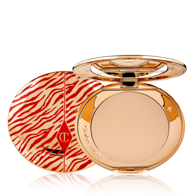 An open, pressed powder compact for medium skin tones with a mirrored lid, in gold-coloured packaging with red-coloured tiger stripes on the lid.