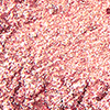 Close-up swatch of a shimmery rose-gold eyeshadow pigment. 
