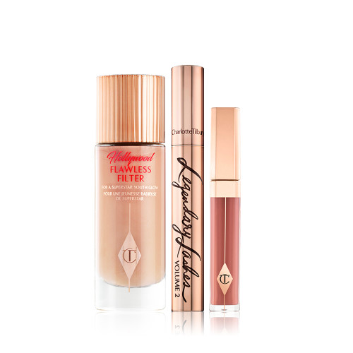 Luminous, dark beige-coloured primer in a glass bottle with gold-coloured lid, mascara in gold-coloured tube and lid, and liquid lipstick in a nude pinky brown colour. 
